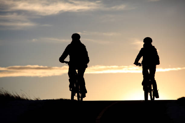 istock Silhouette of Two Cyclists Biking Down A Rural Paved Pathway 1224429326