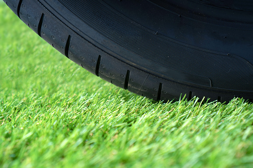 Durable artificial grass lawn concept with wheel tire on the green synthetic turf.