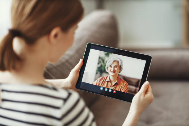 jovem que tem chamada de vídeo com mãe idosa em tablet - 13601 - fotografias e filmes do acervo