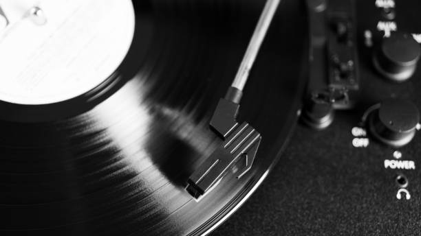 istock Black and white vinyl needle stylus on rotating black vinyl disk with copy space. Top view of vinyl record player. 1224435168