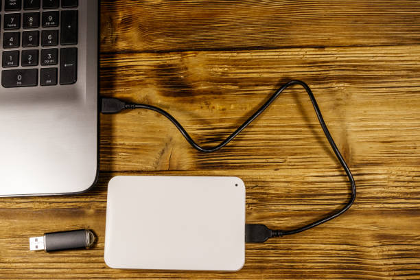 istock External HDD connected to laptop computer and USB flash drive on a wooden desk. Top view. Concept of data storage 1224435393