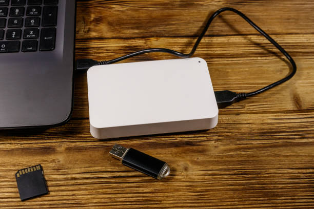 istock External HDD connected to laptop computer, SD memory card and USB flash drive on a wooden desk. Concept of data storage 1224435395