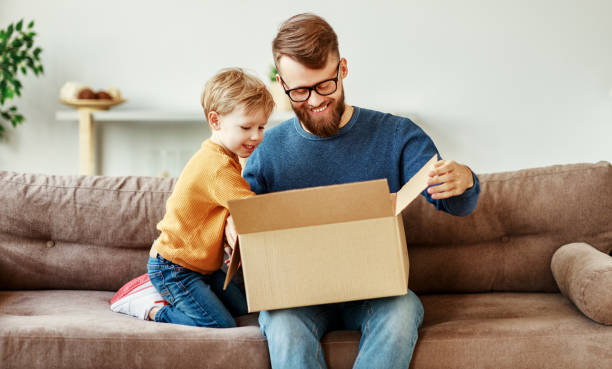 Father and son unpacking delivery box on couch