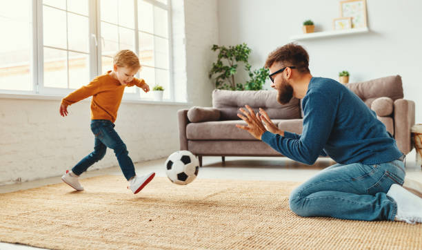 père enseignant le fils pour jouer au football - soccer child indoors little boys photos et images de collection