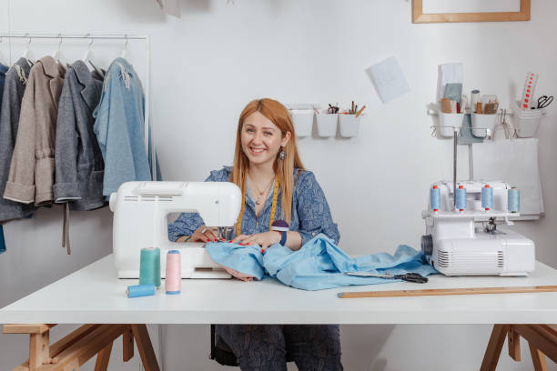 istock tailor smiles in her studio while working on a sewing machine. Fashion Designer Works 1224438656