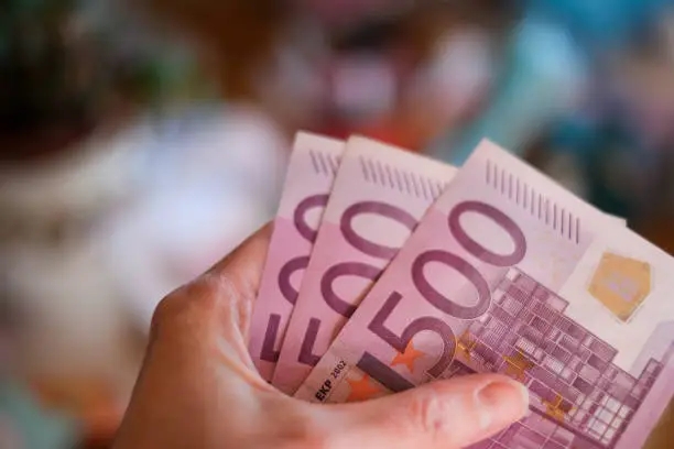 close-up of female hand holding three 500 euro notes