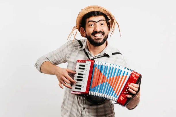 Photo of Brazilian man wearing traditional clothes for Festa Junina - June festival - playing toy accordion