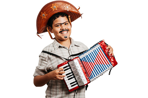 Brazilian boy wearing typical clothes for the Festa Junina - June festival - playing toy accordion