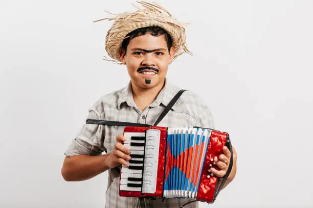 Photo of Brazilian boy wearing typical clothes for the Festa Junina - June festival - playing toy accordion