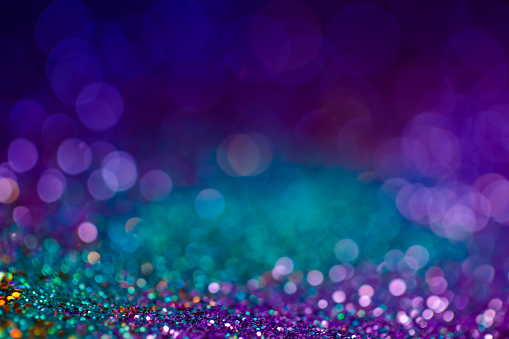 Festive bokeh glitters background, abstract shiny backdrop with circles,modern design overlay with sparkling glimmers. Blue, purple and green backdrop glittering sparks with glow effect