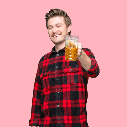 One person of with short hair caucasian young male celebratory toast in front of colored background wearing shirt who is drinking and holding drink