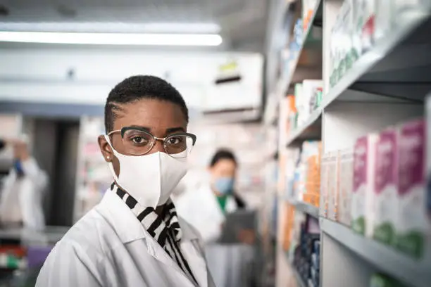 Photo of Portrait of female pharmacist with face mask at pharmacy
