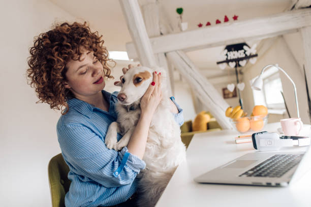 istock Woman cuddling her dog while working at home 1224454029