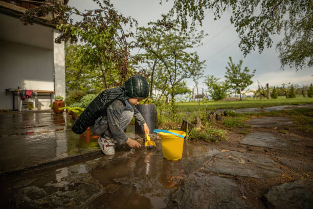 istock Cute boy playing in back yard with bucket and shovel after rain 1224462768