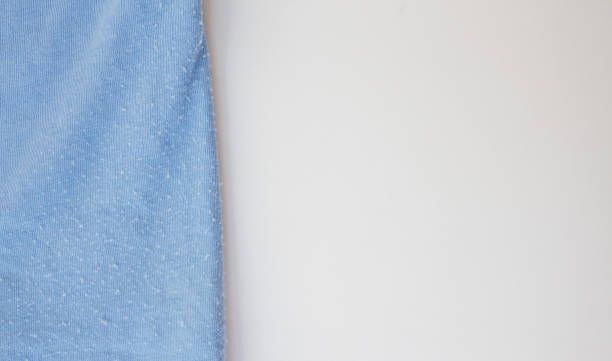 istock Blue clothes in spools on white background close-up with copy space. Problem of poor quality clothing and quick wear 1224464004