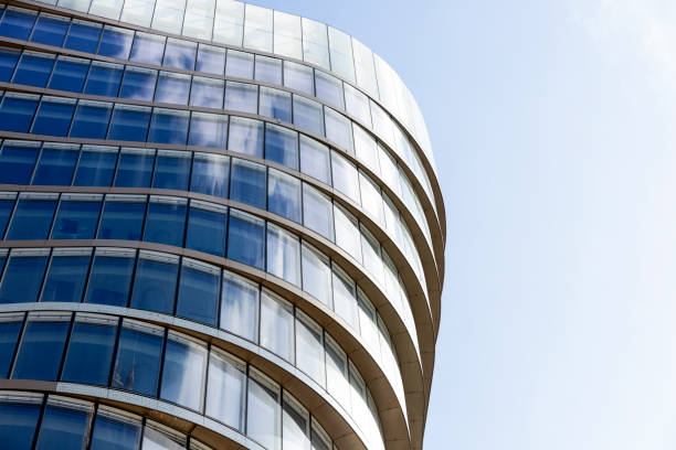 Low angle view of modern office building with reflection, skyscrapers, blue sky background with copy space, full frame horizontal composition