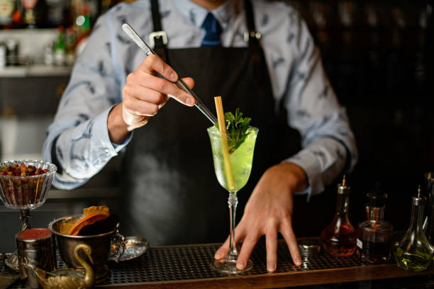 istock barman decorates ready-made cocktail with two sticks by mint leaves using tweezers 1224465514