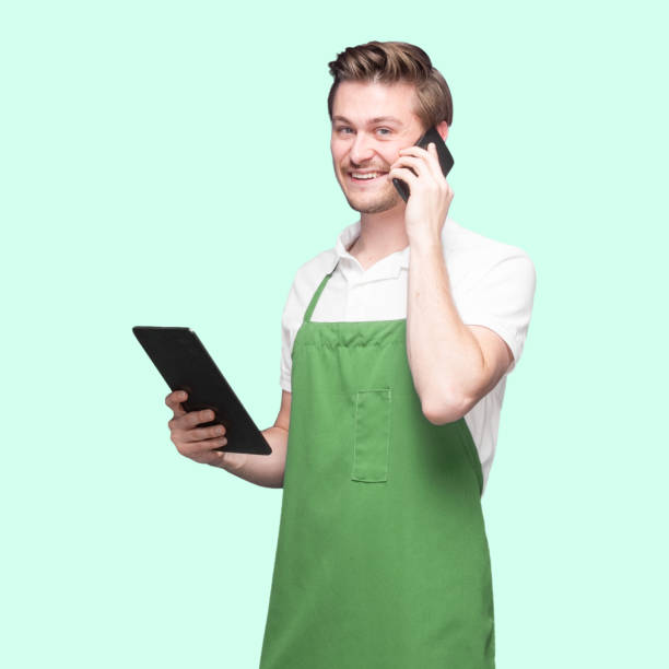 istock Caucasian male barista standing wearing apron and using touch screen 1224465863