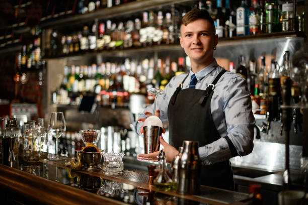 istock Young handsome bartender holds in his hands steel shaker and empty glass 1224466672