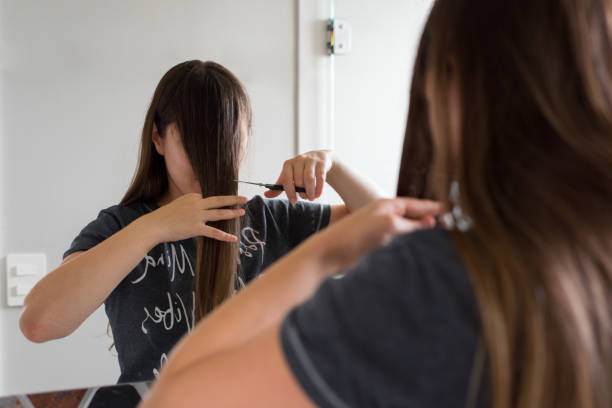 mujer cortando su propio flequillo - flequillo fotografías e imágenes de stock