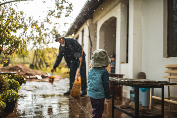 istock Young man sweeping water from front yard on rainy day 1224472677