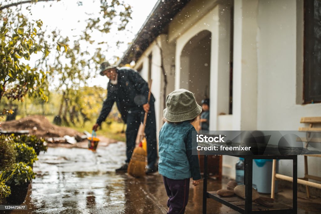 Young man sweeping water from front yard on rainy day Flood Stock Photo