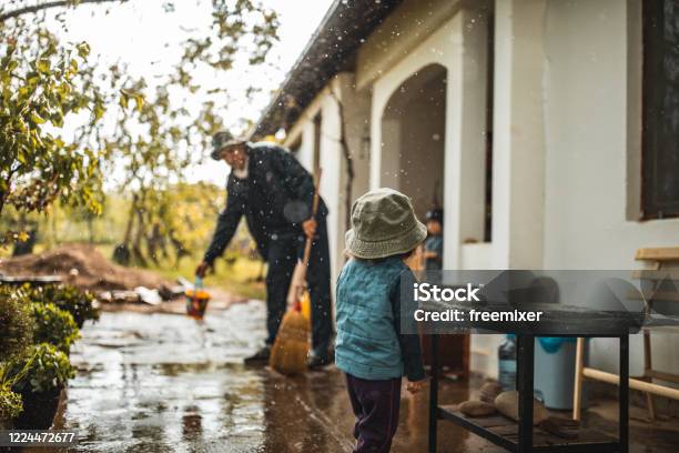 Young Man Sweeping Water From Front Yard On Rainy Day Stock Photo - Download Image Now