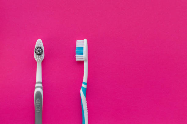 istock Two multi-colored toothbrushes on a pink background. The view from the top. Close up. 1224477240