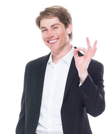 Waist up of aged 20-29 years old caucasian male businessman in front of white background wearing shirt who is cheerful and showing ok sign