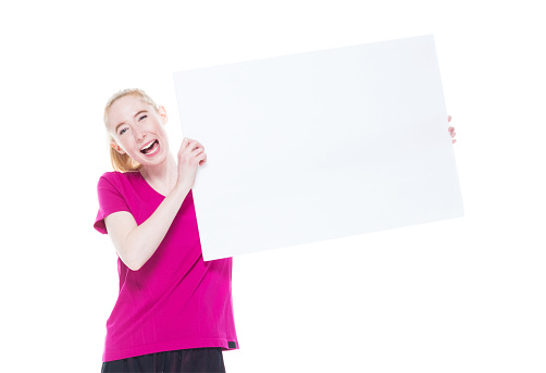 Front view of aged 20-29 years old who is beautiful caucasian female exercising in front of white background who is happy who is showing with hand and holding placard with copy space
