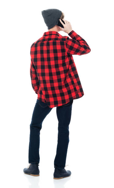 istock Caucasian male hipster standing in front of white background wearing jeans and using mobile phone 1224481149
