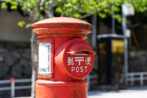 Old japanese post box on street bokeh background. Translation: \