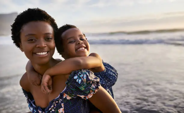 Shot of a young woman spending time at the beach with her adorable daughter