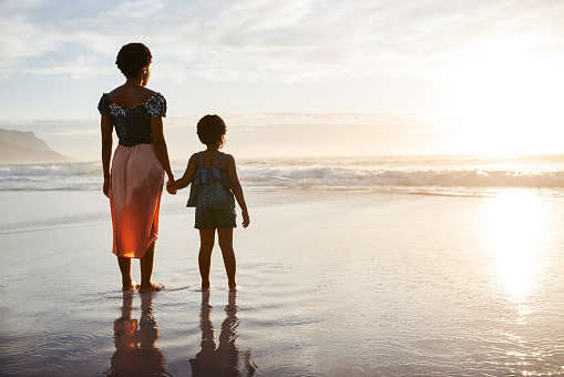 Shot of a young woman spending time at the beach with her adorable daughter