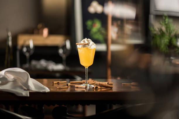 Yellow drink with whip cream and cinnamon on a table with a blurred background