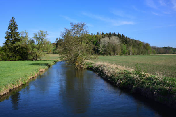 istock Quiet landscape by the river in spring with delicate meadows and trees against a blue sky in Bavaria / Germany 1224502247