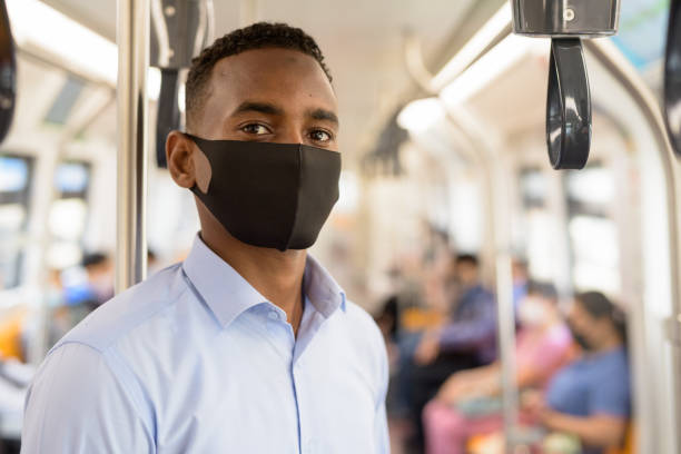 기차 내부의 거리와 함께 서 코로나 바이러스 발병으로부터 보호를위한 마스크를 가진 젊은 아프리카 사업가 - inner city 뉴스 사진 이미지