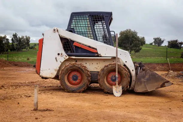 Small white and red mechanical digger truck moving gravel on a construction site