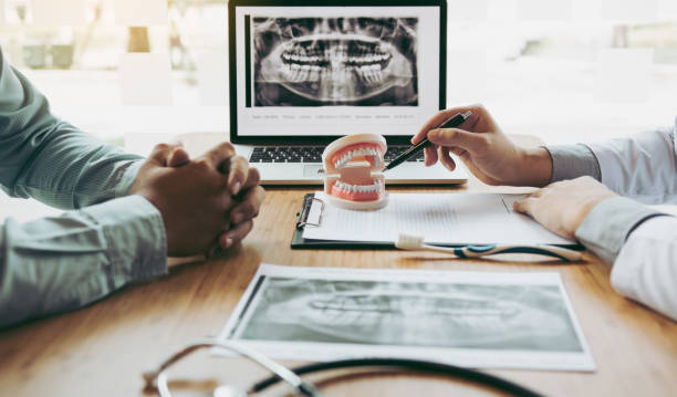 imagen de rayos x apuntando a la mano del dentista en la computadora portátil y hablando con el paciente sobre medicamentos y tratamiento de cirugía. - dental implant dental hygiene dentures prosthetic equipment fotografías e imágenes de stock