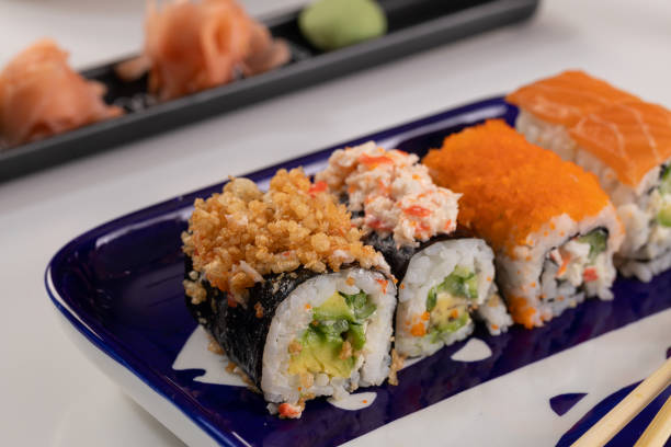 set de sushi y rollos con salmón y atún, aguacate, california, maki, salsa de soja, palillos de primer plano. - maki sushi japanese culture food and drink still life fotografías e imágenes de stock