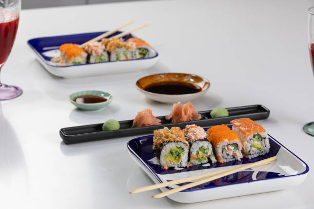 set von sushi und brötchen mit lachs und thunfisch, avocado, california, maki, sojasauce, essstäbchen aus nächster nähe. - maki sushi japanese culture food and drink still life stock-fotos und bilder