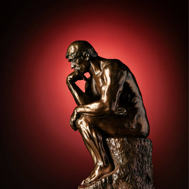 Thinker on Red A bronze replica statue of Rodin's Thinker on a red background with vignette bronze statue stock pictures, royalty-free photos & images