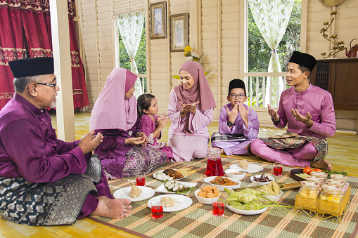 Muslim family saying prayers before meal