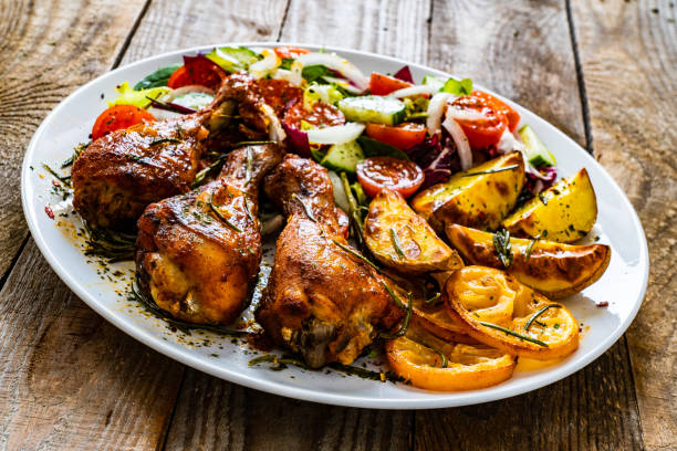 istock Roast chicken drumsticks and vegetables served on wooden table 1224510555