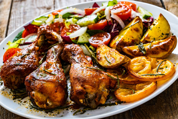istock Roast chicken drumsticks and vegetables served on wooden table 1224510652