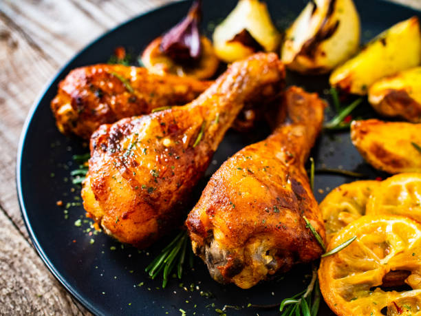 istock Roast chicken drumsticks and vegetables served on wooden table 1224511620