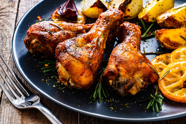 istock Roast chicken drumsticks and vegetables served on wooden table 1224511660