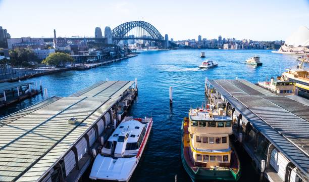 sydney harbour austrália em um dia ensolarado e azul céu com as cores turquesas da baía e escritórios de arranha-céus da cidade ao fundo - circular quay - fotografias e filmes do acervo