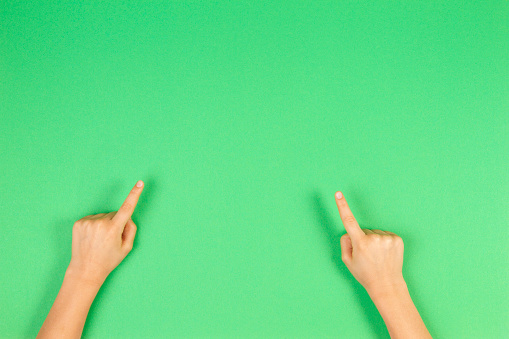 Child hands pointing on green background.