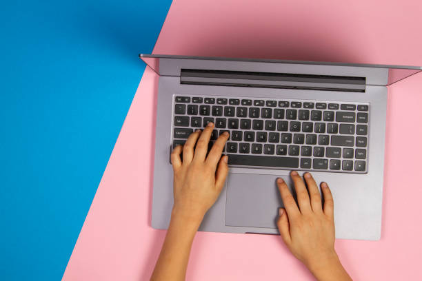 istock Kid hands typing on laptop computer keyboard, top view, pink and blue background 1224514941